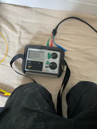 a person holding a digital meter on a bed