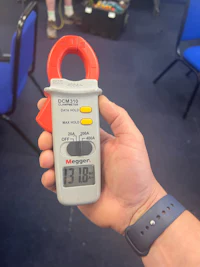 a person holding an electronic clamp meter in front of a group of people