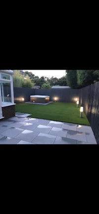 a garden with artificial grass and lighting at night